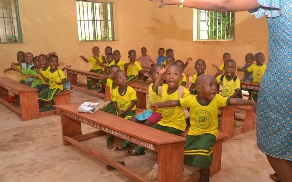 Donated school desks with students rejoicing.