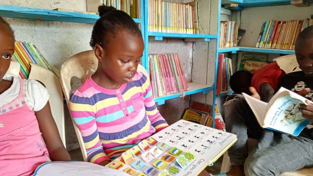 Image of a young girl reading a book in a traditional library in sub-Saharan Africa. 