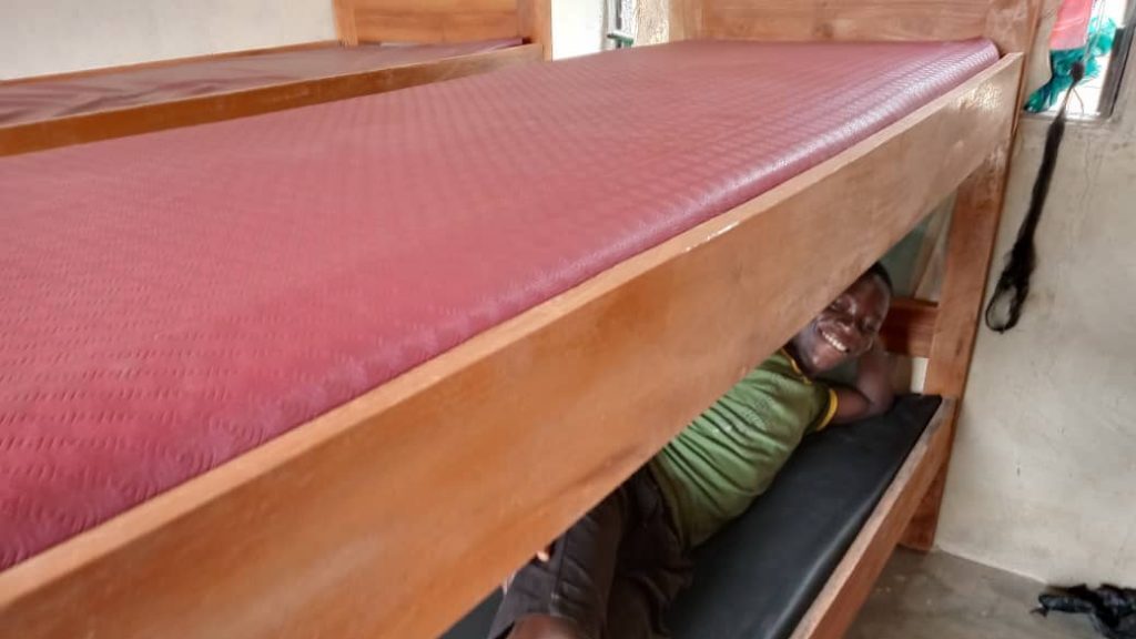 A young boy smiling while laying on the new supplied bed frames and mattresses.