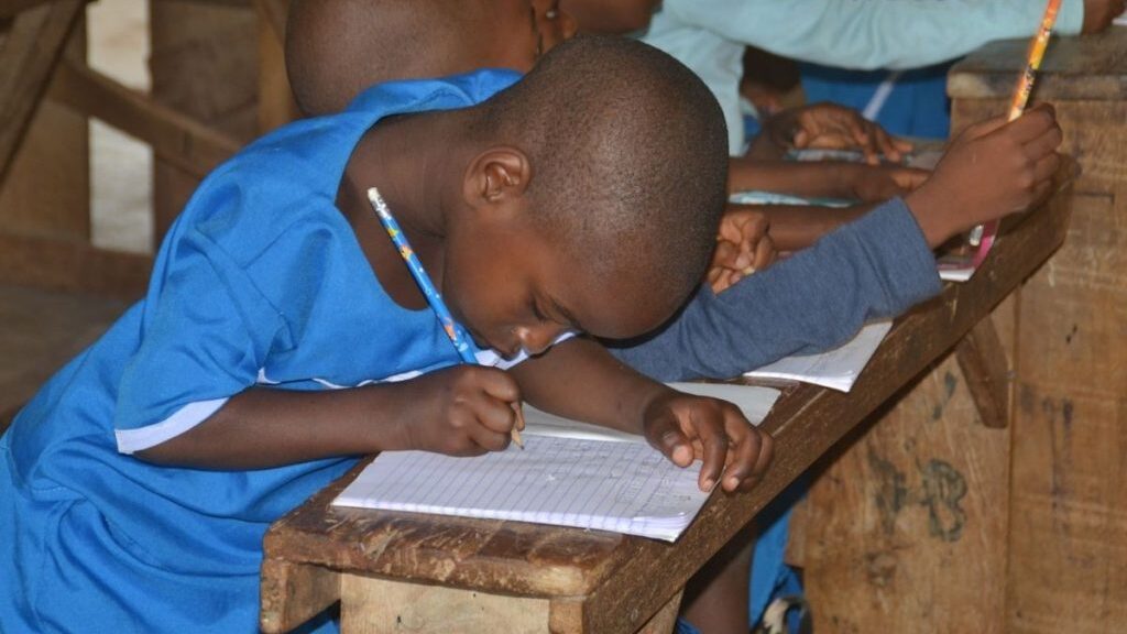 Image of a student writing with one of the donated school resources showing our impact in advancing education.
